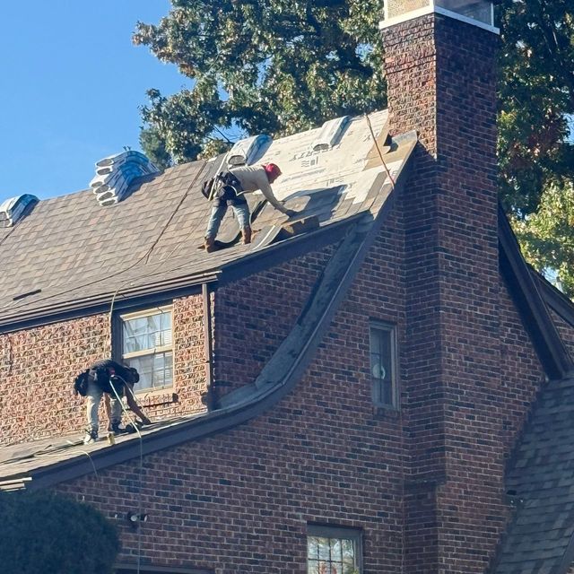 Roofers removing old shingles on a steep brick home in South Hills, Pittsburgh, PA.